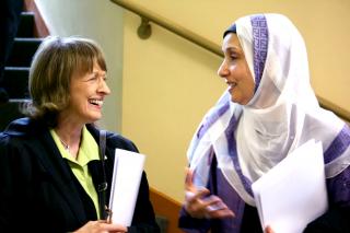 Two women, one Unitarian Universalist and one Muslim, smile at each other.