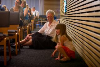 Older woman and small girl sit on the floor during worship at Unitarian Fellowship of Lawrence, Kansas.