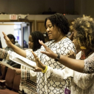 Black women raising their hands in worship
